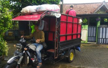 Petugas pengumpul sampah mandiri menggunakan motor roda tiga dengan bak tertutup terpal biru sedang bersiap mengangkut sampah perumahan di Pamulang menuju TPA swasta di Ciledug pada Januari 2026.