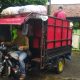 Petugas pengumpul sampah mandiri menggunakan motor roda tiga dengan bak tertutup terpal biru sedang bersiap mengangkut sampah perumahan di Pamulang menuju TPA swasta di Ciledug pada Januari 2026.