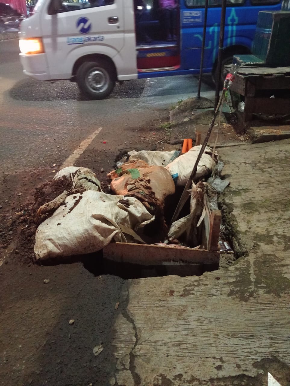 Kondisi jalan berlubang dan tumpukan tanah bekas galian kabel optik di depan Apotek Syifa, Jl. Swadaya Raya Larangan, Tangerang yang membahayakan pengendara motor dan pejalan kaki pada Januari 2026