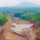 Pemandangan bangunan Sabo Dam beton di aliran sungai hulu lereng Gunung Merapi dengan latar belakang awan.