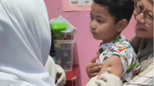 Petugas medis dari Puskesmas Bakti Jaya sedang memberikan imunisasi campak kepada seorang anak di sebuah Taman Kanak-kanak.