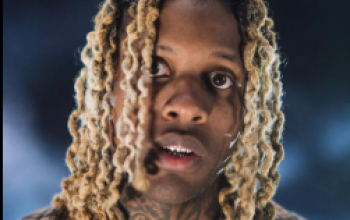 Potret Lil Durk saat menerima penghargaan atau tampil di panggung dengan gaya khas perhiasan OTF.