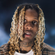 Potret Lil Durk saat menerima penghargaan atau tampil di panggung dengan gaya khas perhiasan OTF.