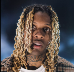 Potret Lil Durk saat menerima penghargaan atau tampil di panggung dengan gaya khas perhiasan OTF.