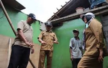 Petugas Disperkimtan sedang melakukan pengukuran dan verifikasi struktur bangunan rumah tua yang berdinding bambu/papan.