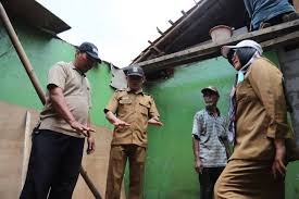 Petugas Disperkimtan sedang melakukan pengukuran dan verifikasi struktur bangunan rumah tua yang berdinding bambu/papan.