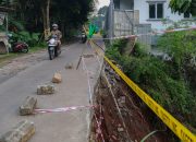 Petugas BPBD Tangsel sedang memasang garis pembatas (police line) dan rambu peringatan di sisi jalan yang longsor di Ciater.