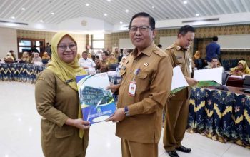 Sekda Kota Tangerang Herman Suwarman sedang menyerahkan dokumen SK secara simbolis kepada perwakilan ASN yang mengenakan seragam batik korpri di dalam ruangan pertemuan.