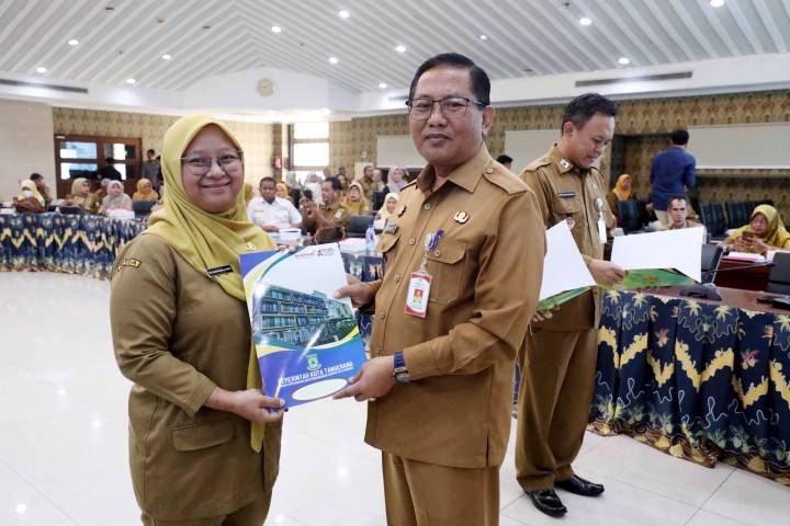 Sekda Kota Tangerang Herman Suwarman sedang menyerahkan dokumen SK secara simbolis kepada perwakilan ASN yang mengenakan seragam batik korpri di dalam ruangan pertemuan.