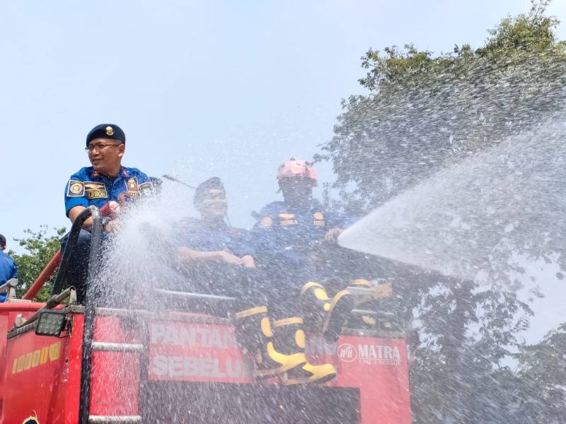STERILISASI JALUR UTAMA: Personel BPBD Kota Tangerang melakukan penyiraman dan pembersihan material minyak curah di Jalan Jenderal Sudirman, Kelurahan Babakan, Tangerang, Senin (18/5/2026). Langkah darurat ini dilakukan menyusul insiden kecelakaan beruntun sembilan pemotor akibat kebocoran truk tangki.