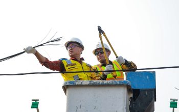 Petugas Dinas Perhubungan dan Satpol PP Kota Tangerang Selatan saat memotong dan menggulung kabel fiber optik liar yang semrawut di atas tiang utilitas Jalan Merpati, Ciputat.