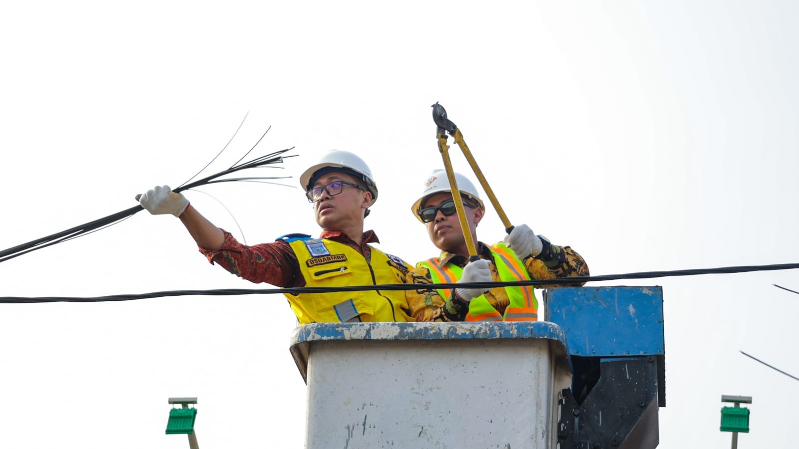 Petugas Dinas Perhubungan dan Satpol PP Kota Tangerang Selatan saat memotong dan menggulung kabel fiber optik liar yang semrawut di atas tiang utilitas Jalan Merpati, Ciputat.