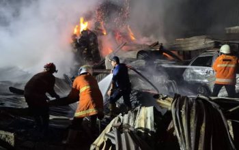 Petugas BPBD Kota Tangerang menyemprotkan air ke arah bangunan Gudang DC Jaya yang terbakar di Tanah Tinggi tahun 2026.