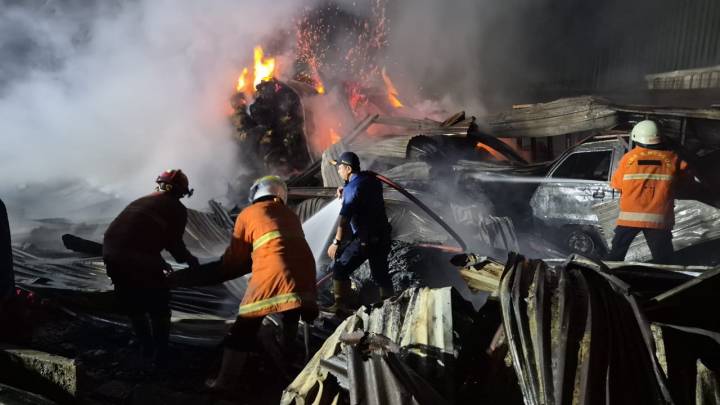 Petugas BPBD Kota Tangerang menyemprotkan air ke arah bangunan Gudang DC Jaya yang terbakar di Tanah Tinggi tahun 2026.